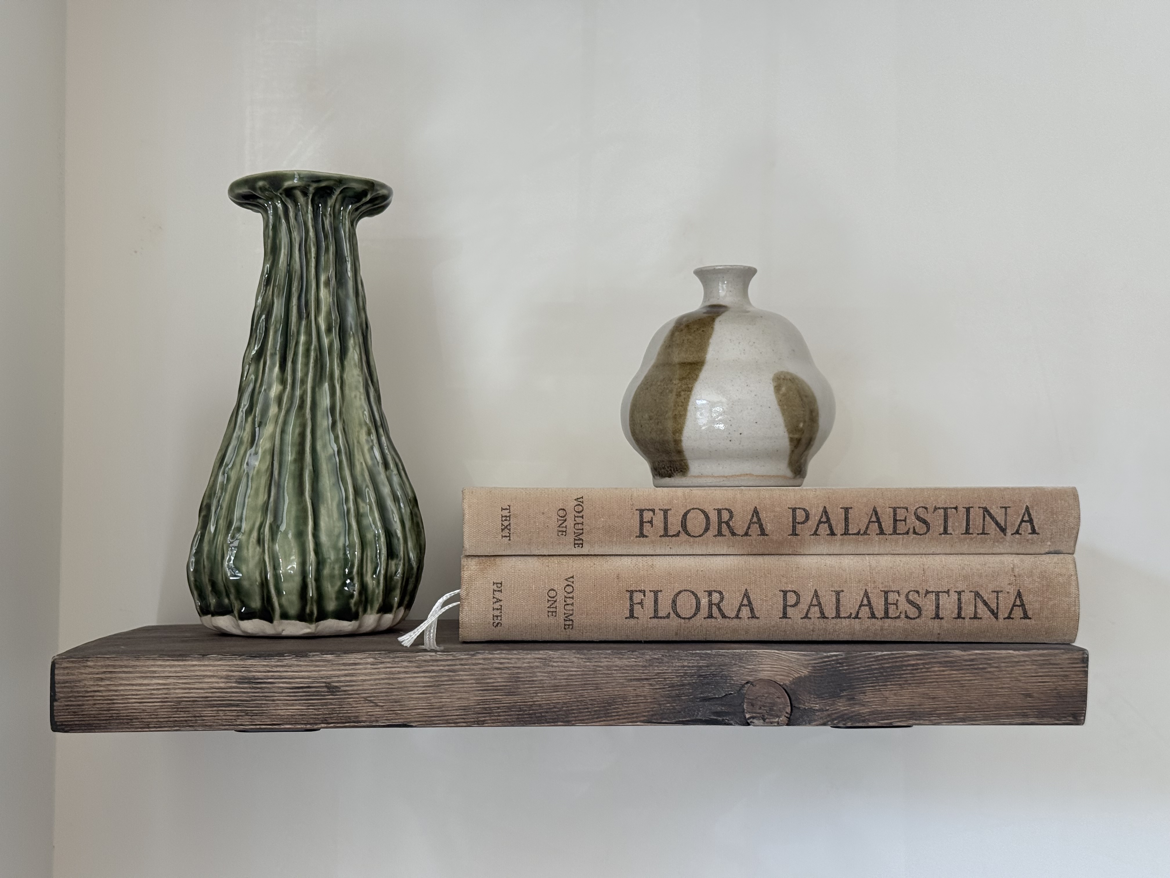 Handmade ceramic vases arranged on a wooden shelf above books